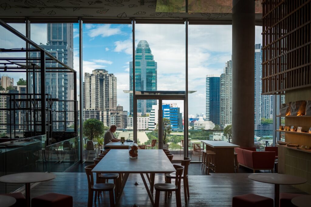 growth digital nomad culture — Modern cafe interior with city view through windows