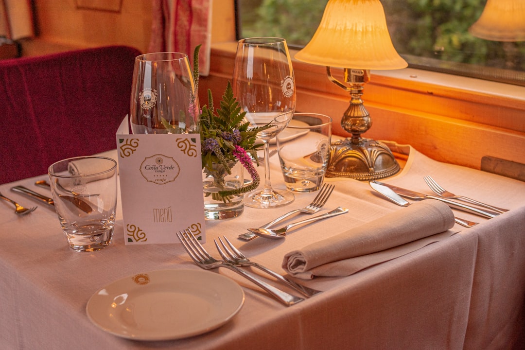 luxury train journeys redefine — a white-glove dining car service with crystal glasses and panoramic mountain views through wide carriage windows