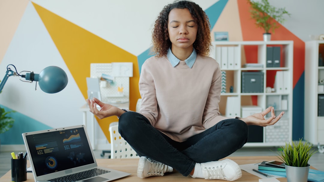 mindful productivity new success — professional meditating at desk with laptop showing calm interface