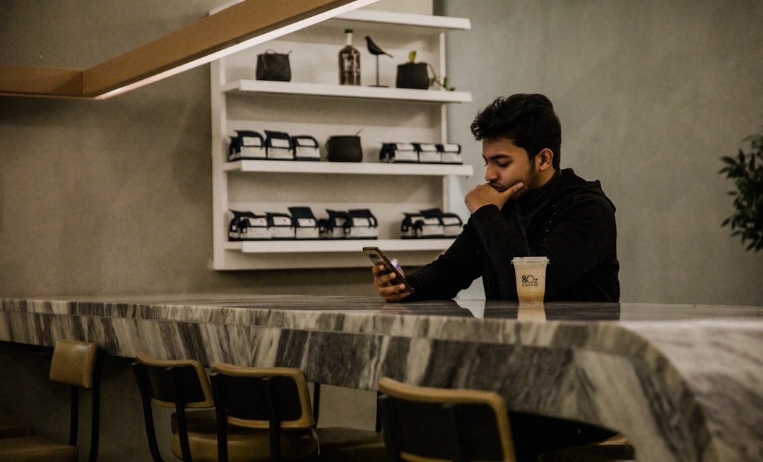 alternative investments younger investors — a young person reviewing investment portfolio metrics on a smartphone while sitting at a coffee shop