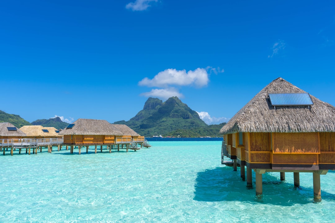 rise remote island tourism — luxury beachfront villa with overwater bungalow architecture