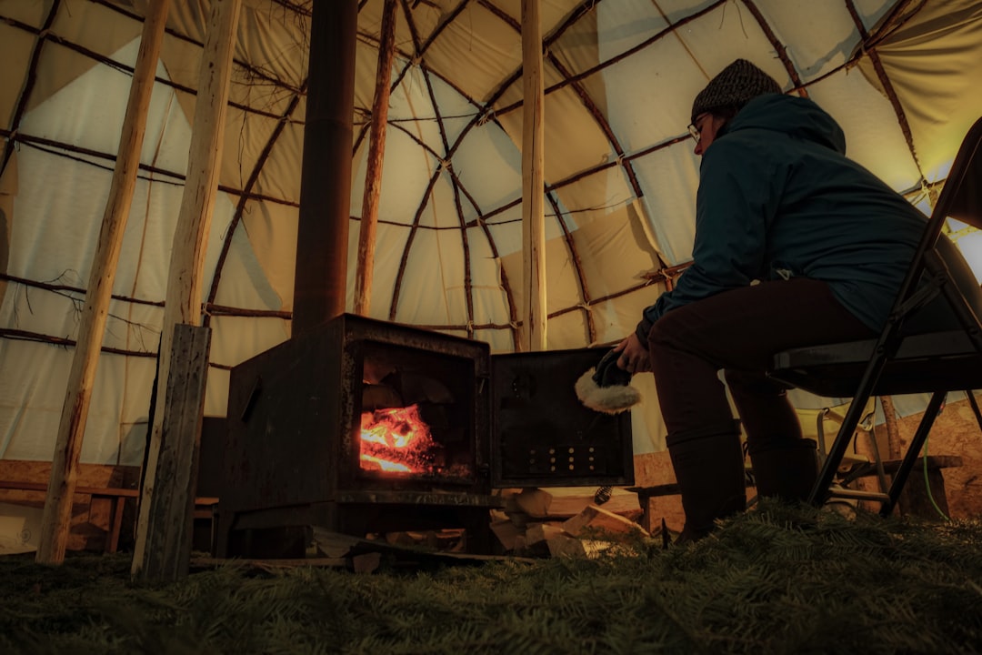 rise luxury camping glamping — glamping pod interior with plush bedding and wood-burning stove during winter evening