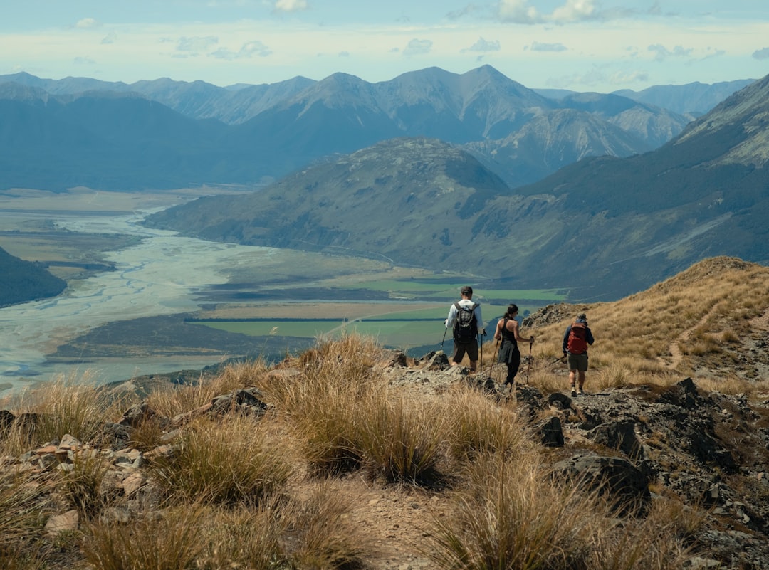 mountain destinations tourism growth — family hiking on alpine trail with scenic valley backdrop
