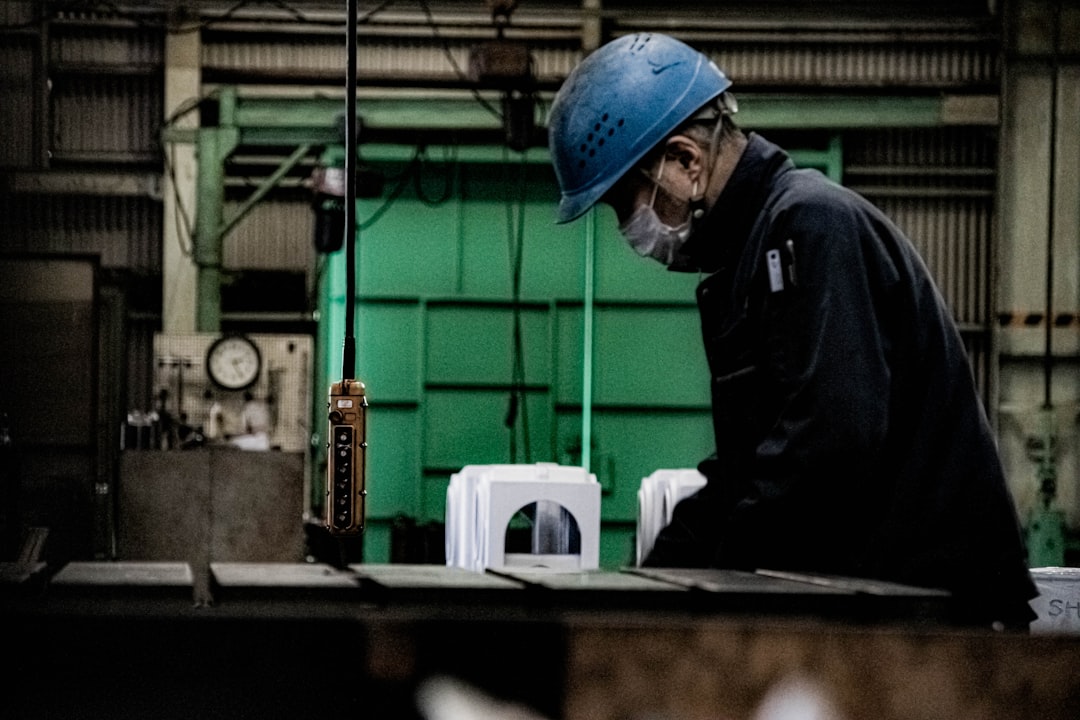 modular construction ground global — worker in hard hat checking quality inside climate-controlled factory setting