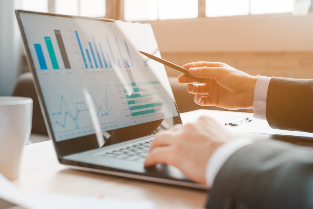 major sporting events transform — financial analysts reviewing data charts and GDP statistics on a laptop in a modern office