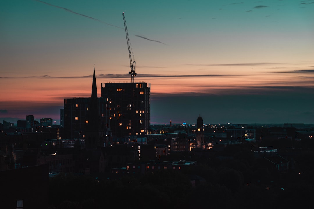 rise mixed-use developments rapidly—construction site with cranes overlooking city skyline at dusk