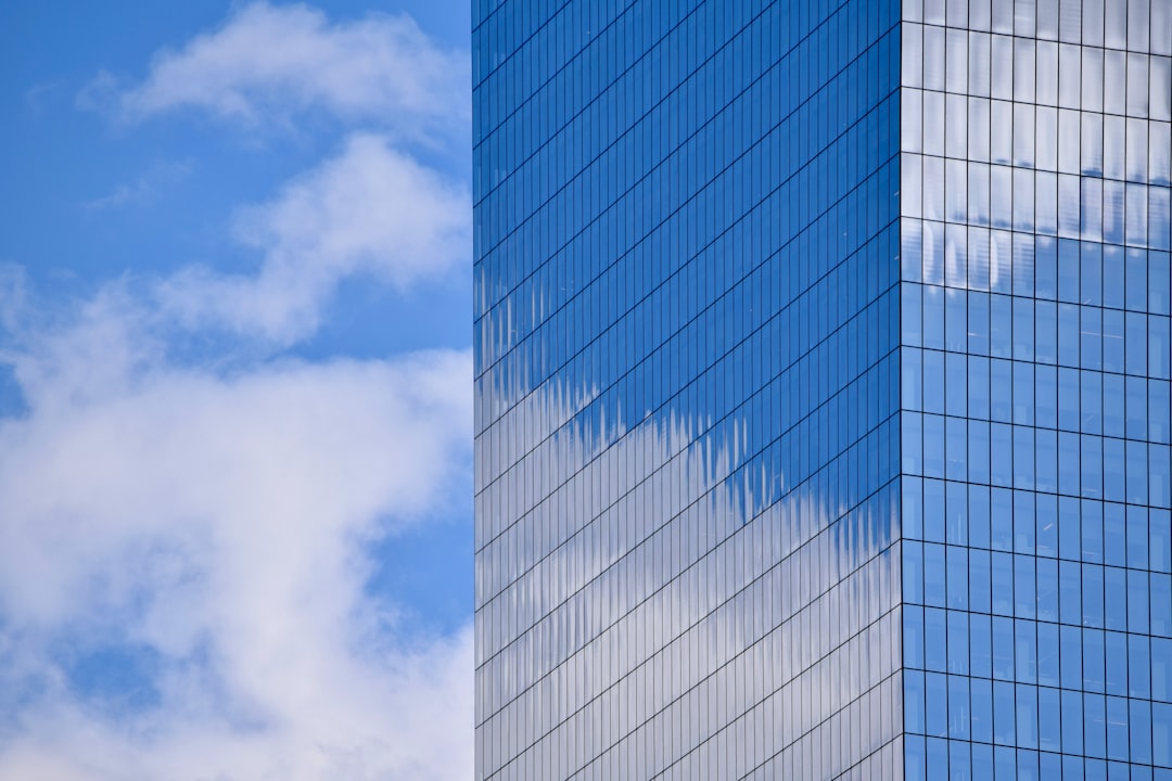 future office buildings era — modern glass office tower reflecting clouds in urban skyline