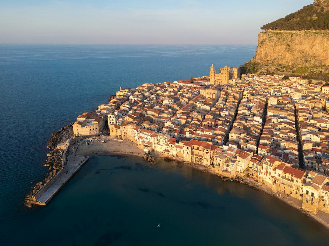 rise film tourism impact — aerial view of a Mediterranean coastal town with film crews visible