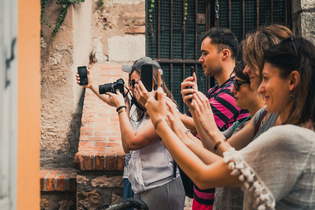rise film tourism impact — tourists taking selfies at a recognizable film location with organized tour guides nearby